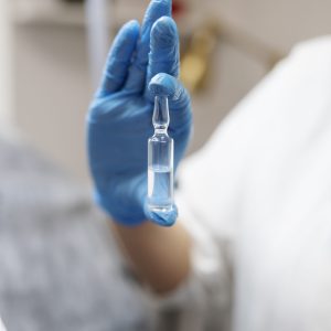 hand-with-glove-holding-vial